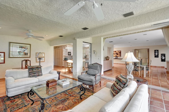 tiled living room with ceiling fan and a textured ceiling