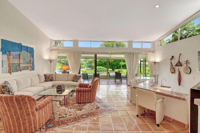 living room with light tile patterned flooring, high vaulted ceiling, plenty of natural light, and sink