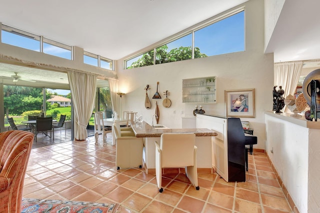 interior space with a kitchen bar, light tile patterned floors, plenty of natural light, and ceiling fan