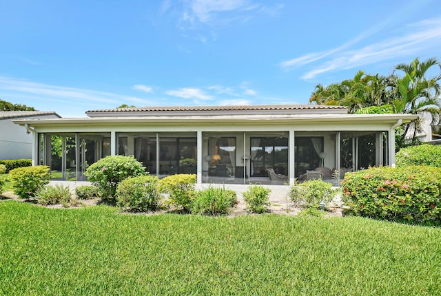 rear view of property featuring a lawn and a sunroom