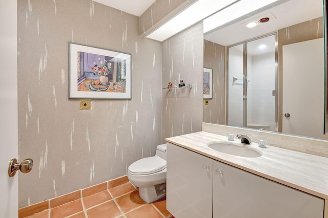 bathroom with toilet, vanity, and tile patterned floors