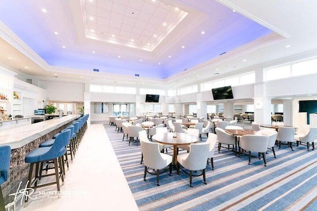 dining area with a towering ceiling, a tray ceiling, and light colored carpet