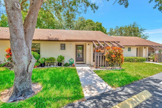 single story home with stucco siding, a front lawn, and roof with shingles