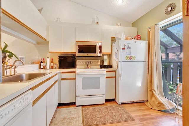 kitchen with white cabinetry, white appliances, sink, vaulted ceiling, and light hardwood / wood-style floors