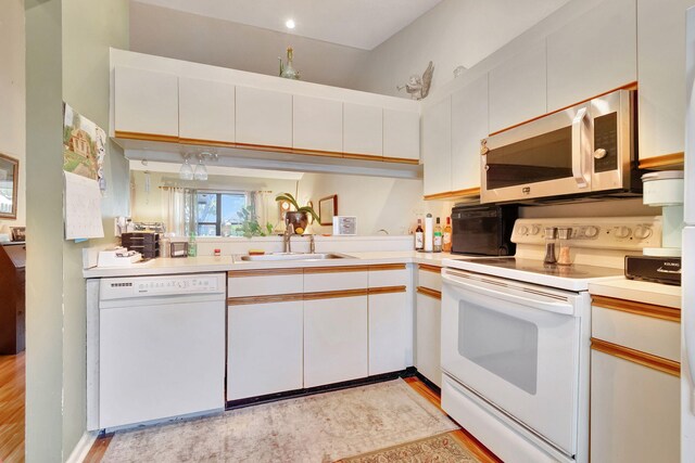 kitchen featuring white cabinetry, light hardwood / wood-style flooring, white appliances, and sink