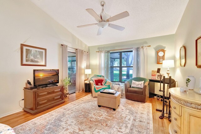 living room featuring light hardwood / wood-style floors, vaulted ceiling, and ceiling fan