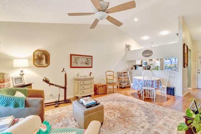 living room featuring wood-type flooring, high vaulted ceiling, and ceiling fan