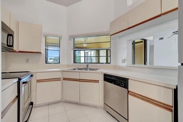 kitchen with appliances with stainless steel finishes, cream cabinets, sink, ceiling fan, and light tile floors