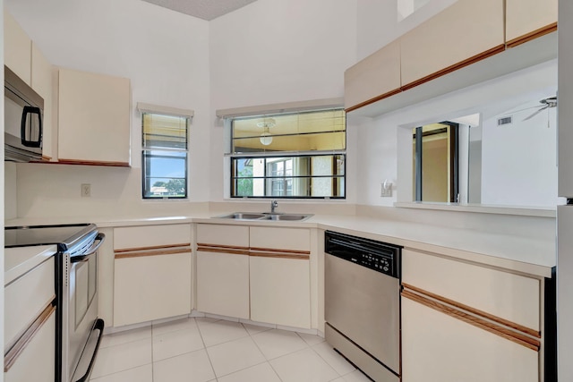 kitchen featuring a sink, cream cabinets, stainless steel appliances, light tile patterned flooring, and light countertops