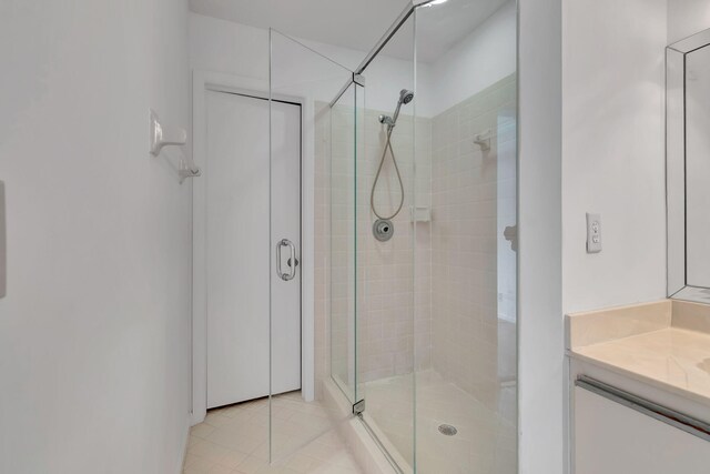 bathroom with a shower with shower door, tile flooring, and vanity