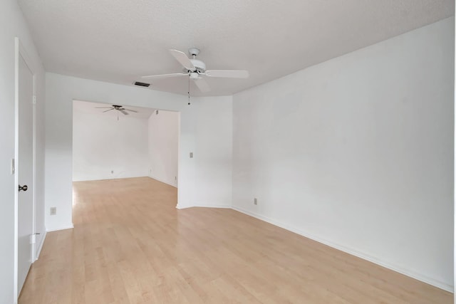 spare room with a ceiling fan, visible vents, light wood finished floors, and a textured ceiling