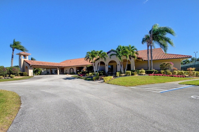 view of front of property with a tile roof, uncovered parking, a front lawn, and stucco siding
