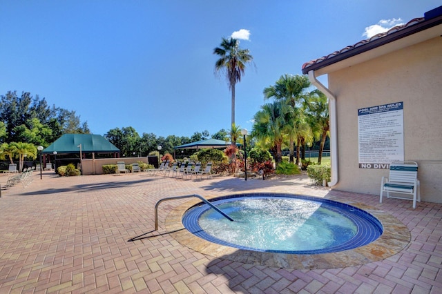 view of swimming pool featuring a hot tub, a patio, and fence