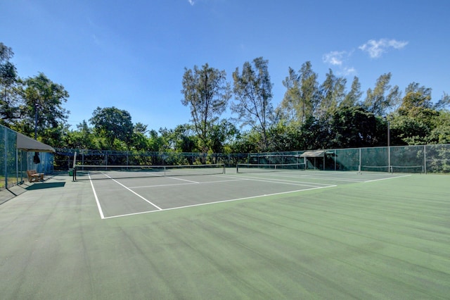 view of tennis court with community basketball court and fence
