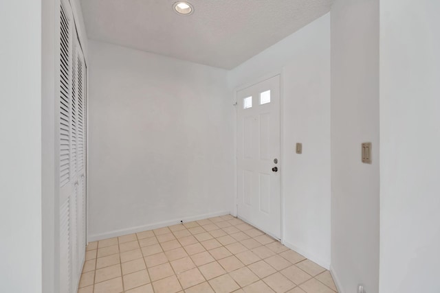 empty room with light tile patterned floors, recessed lighting, baseboards, and a textured ceiling