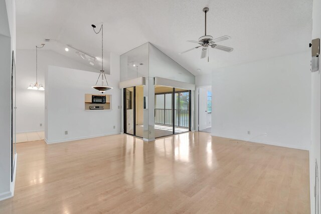 unfurnished living room with wood-type flooring, ceiling fan with notable chandelier, a textured ceiling, track lighting, and high vaulted ceiling