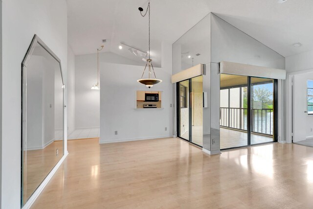 unfurnished living room with high vaulted ceiling, light hardwood / wood-style floors, and rail lighting