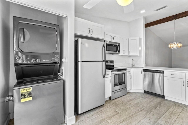 kitchen featuring stacked washer / dryer, white cabinetry, light hardwood / wood-style flooring, and appliances with stainless steel finishes