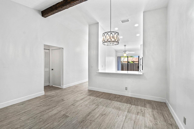 empty room with lofted ceiling with beams, wood-type flooring, and ceiling fan with notable chandelier