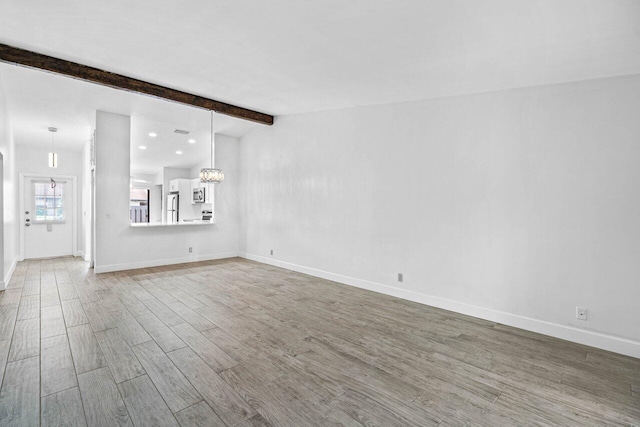 unfurnished living room featuring hardwood / wood-style floors and beam ceiling