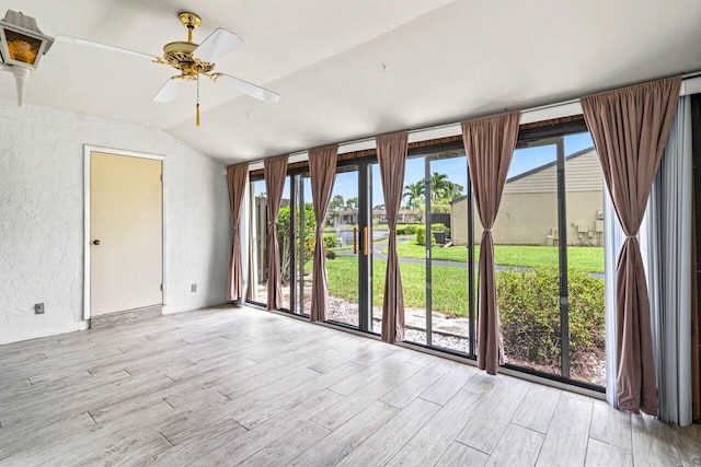 unfurnished room with ceiling fan, lofted ceiling, and light wood-type flooring