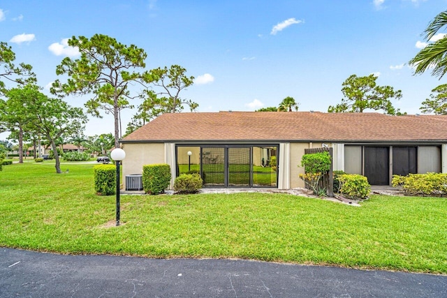 single story home with cooling unit and a front lawn