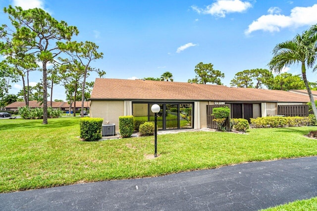 single story home featuring central air condition unit and a front lawn