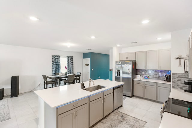 kitchen with an island with sink, appliances with stainless steel finishes, sink, and gray cabinets