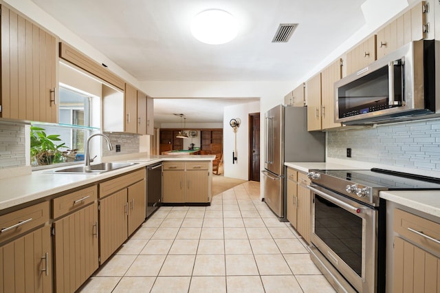 kitchen featuring appliances with stainless steel finishes, tasteful backsplash, sink, pendant lighting, and light tile patterned flooring