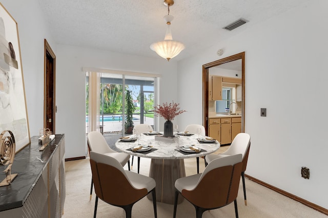 dining room featuring light carpet, sink, and a textured ceiling