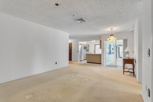 unfurnished living room with light colored carpet and a textured ceiling