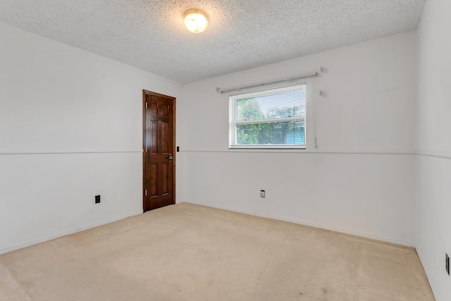 spare room with light colored carpet and a textured ceiling