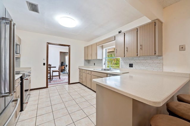 kitchen with kitchen peninsula, tasteful backsplash, sink, light tile patterned floors, and stainless steel range with electric cooktop