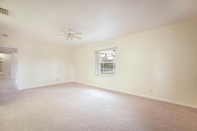 spare room with visible vents, baseboards, light colored carpet, ceiling fan, and a textured ceiling