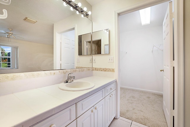 bathroom featuring a textured ceiling, ceiling fan, vanity, baseboards, and a spacious closet