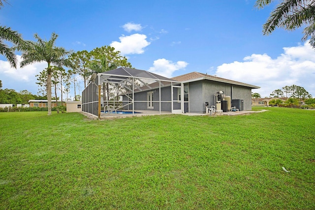 back of house with a lawn, an outdoor pool, a lanai, and stucco siding