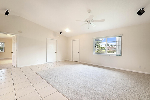 empty room with ceiling fan, light tile patterned flooring, a healthy amount of sunlight, and lofted ceiling