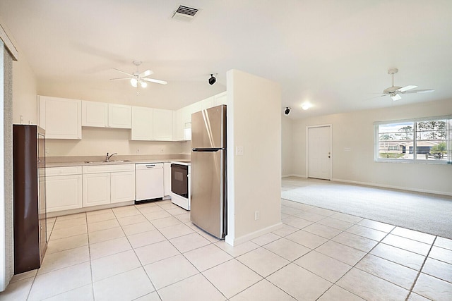 kitchen with stove, white dishwasher, light tile patterned floors, white cabinets, and stainless steel refrigerator