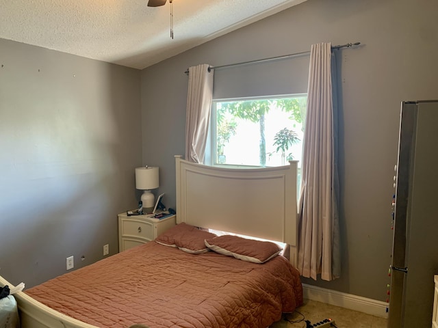 bedroom featuring ceiling fan, a textured ceiling, and stainless steel refrigerator