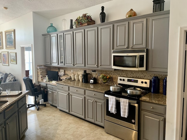 kitchen featuring tasteful backsplash, dark stone countertops, a textured ceiling, and appliances with stainless steel finishes