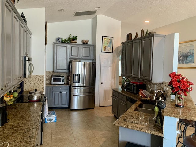 kitchen featuring gray cabinetry, sink, vaulted ceiling, tasteful backsplash, and stainless steel appliances