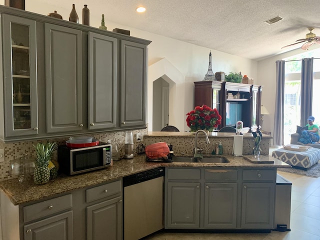 kitchen with gray cabinetry, dark stone counters, sink, a textured ceiling, and appliances with stainless steel finishes