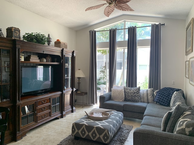 living room with ceiling fan, lofted ceiling, a textured ceiling, and light tile patterned floors