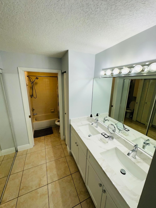 full bathroom with a textured ceiling, tiled shower / bath combo, tile patterned flooring, vanity, and toilet