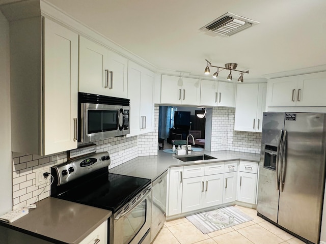 kitchen featuring tasteful backsplash, sink, light tile patterned floors, appliances with stainless steel finishes, and white cabinets