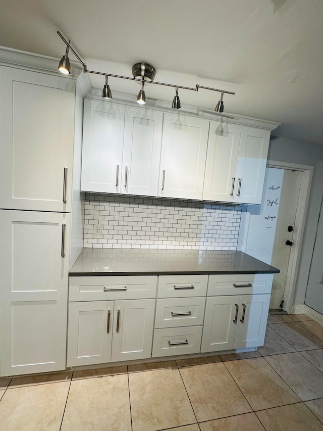 kitchen with tasteful backsplash, white cabinets, and light tile patterned floors