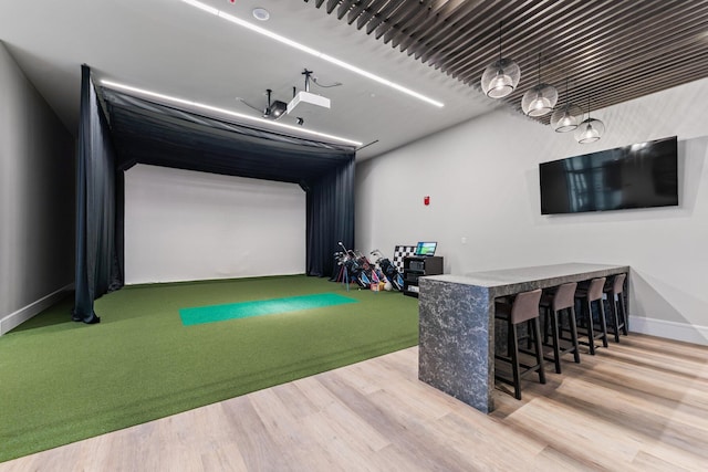 rec room featuring golf simulator, wood finished floors, and baseboards