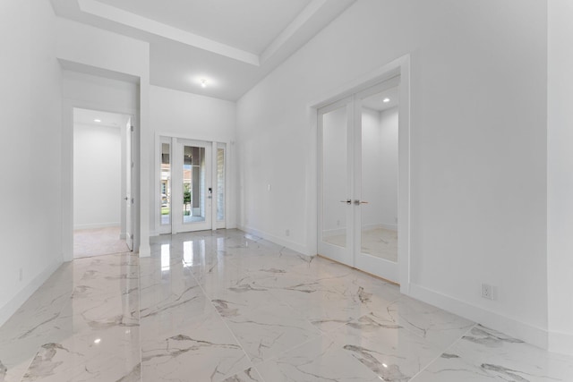 unfurnished room with light tile patterned floors, french doors, and a raised ceiling