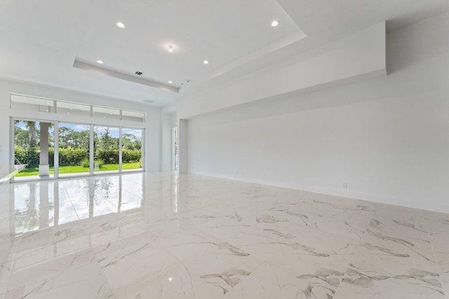 empty room with light tile patterned flooring and a tray ceiling