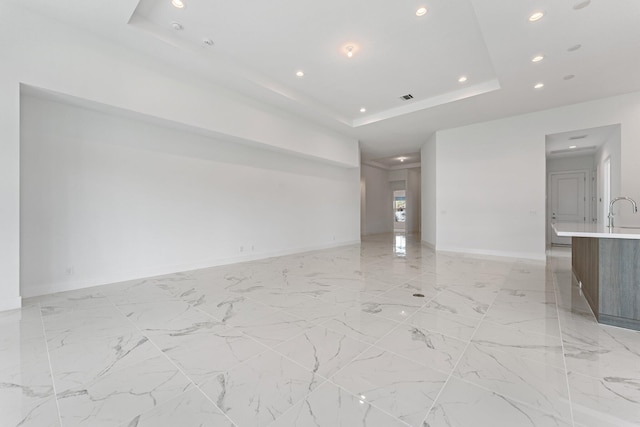 unfurnished living room featuring recessed lighting, visible vents, baseboards, marble finish floor, and a tray ceiling